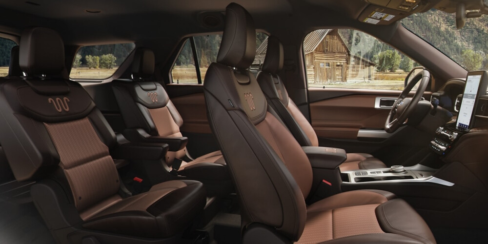 SUV interior with brown leather seats and sleek design. The cabin is spacious with two rows, featuring a modern dashboard and ample legroom. Cozy and luxurious feel.
