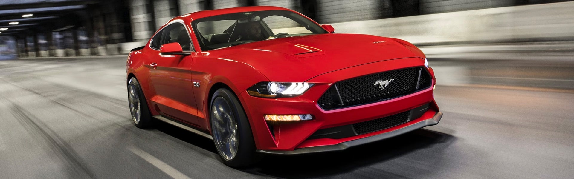 Front view of a red 2024 Ford Mustang driving on the road