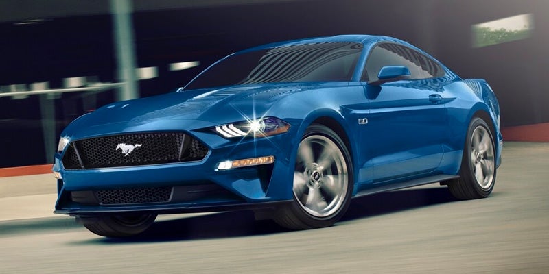 Front view of a blue 2024 Ford Mustang driving on the road
