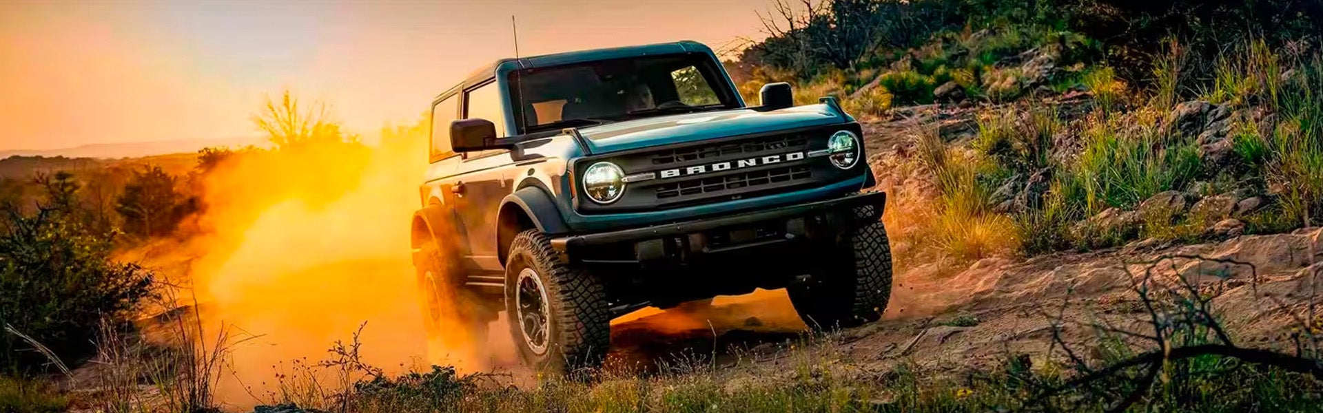 Photo of a 2024 Ford Bronco driving on a rocky terrain during a sunset