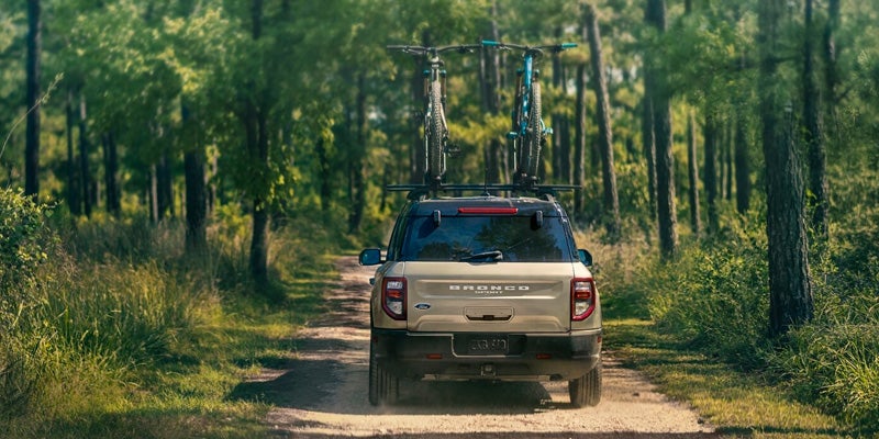Rear view of a 2024 Ford Bronco Sport driving with two bikes mounted on top of it