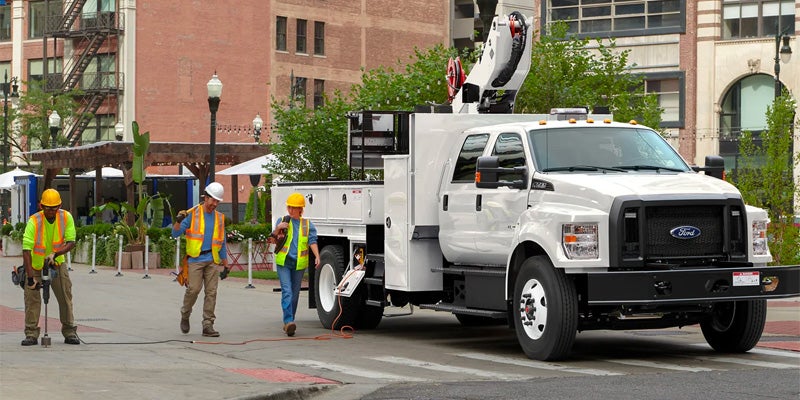 Two workers walking by a 2024 Ford F-650
